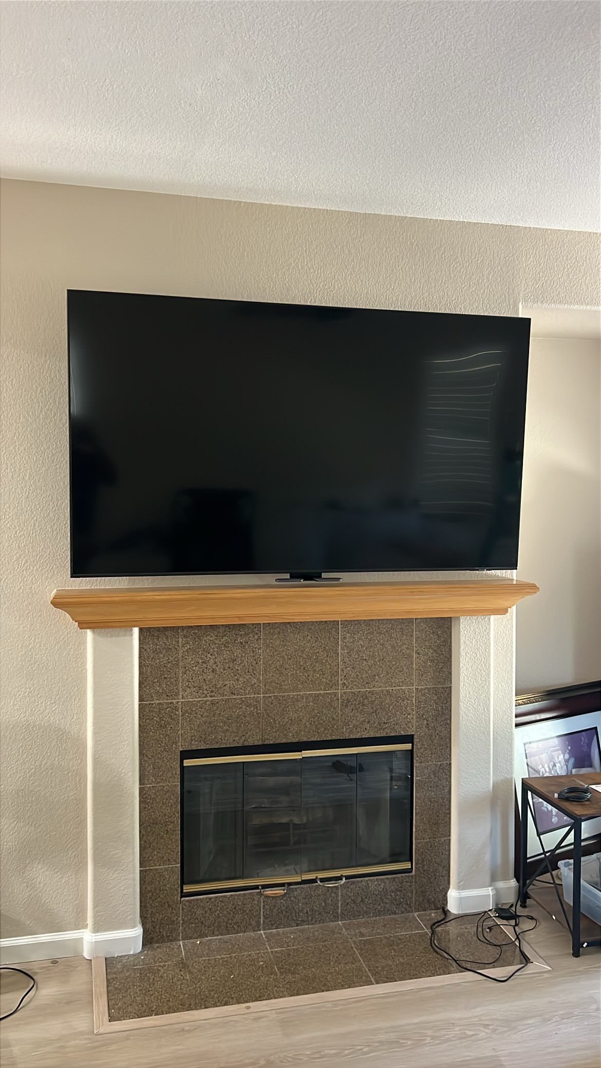 MantelMount TV lowered over a linear fireplace with built-in shelving
